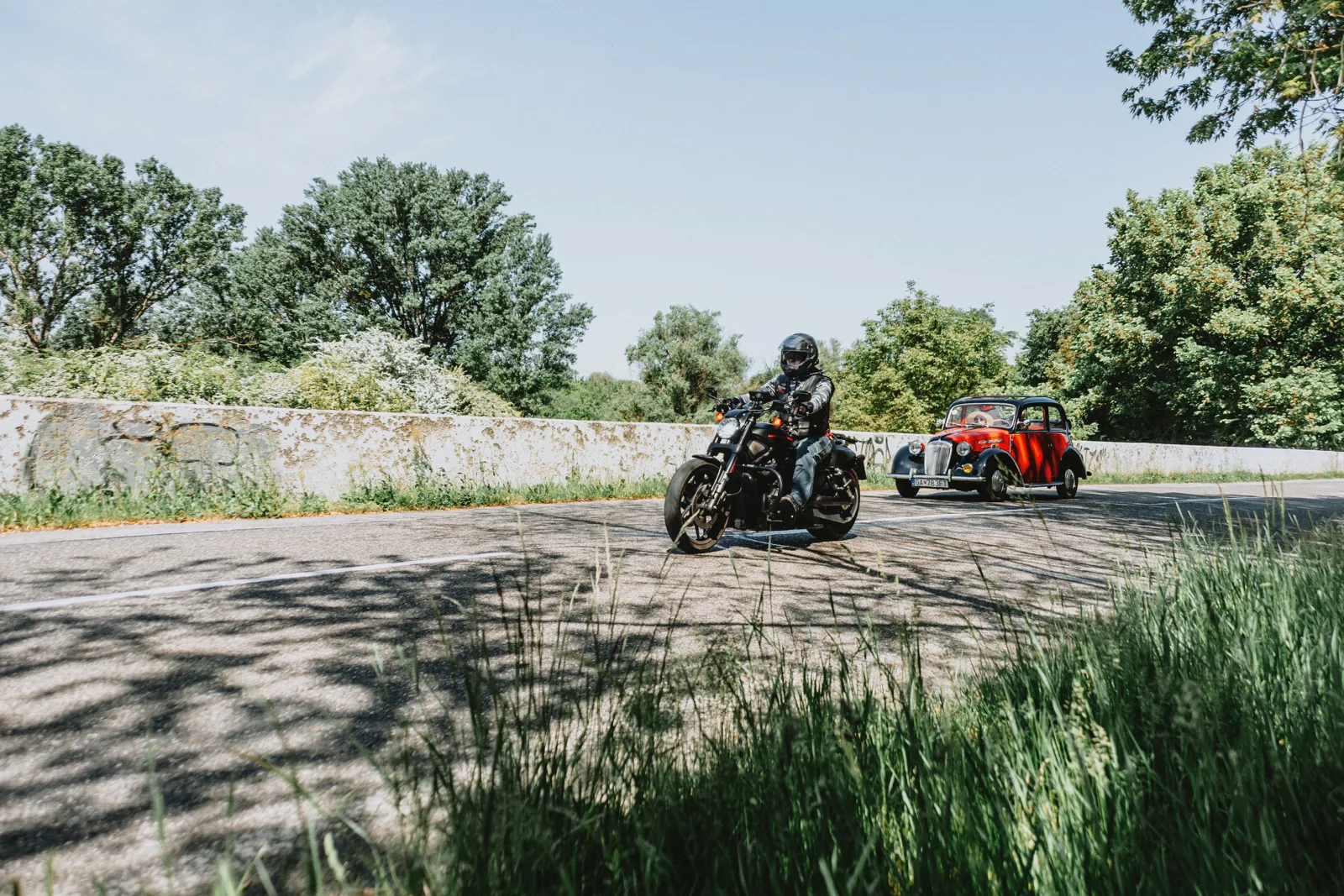 Une moto et une voiture se croisent sur une route de campagne.